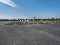 a basketball hoop sits on the corner of an empty parking lot where players are standing