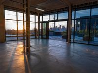 large open space with windows and a floor view at sunset with a skyscraper in the distance