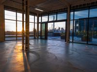 large open space with windows and a floor view at sunset with a skyscraper in the distance