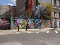 a city side view of a mural on the side of a building with a wall of many colorful paintings, some have different faces