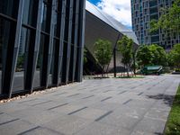 an empty city sidewalk with some benches next to it in the city with tall buildings