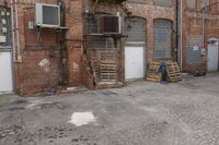 the empty city sidewalk is shown with crates of crates parked outside of it with an open garage and brick building in the background