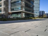 a city sidewalk in front of buildings in the sun light time with a street and grass