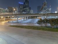 the city skylines are lit up at night from an elevated walkway of an elevated parking area