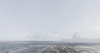 the city is visible from behind an empty air field with footprints on the ground and fog