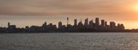 view of skyline from across the lake in front of sun setting over city buildings on horizon