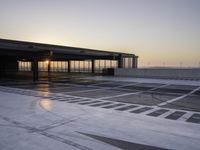 a parking garage at sunrise time with white markings on the floor and gray ground, with a large entrance area beside