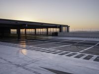 a parking garage at sunrise time with white markings on the floor and gray ground, with a large entrance area beside