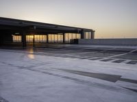 a parking garage at sunrise time with white markings on the floor and gray ground, with a large entrance area beside