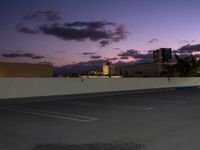 a city skyline and parking lot at dusk with traffic lights on and an orange fire hydrant