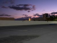 a city skyline and parking lot at dusk with traffic lights on and an orange fire hydrant