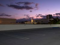 a city skyline and parking lot at dusk with traffic lights on and an orange fire hydrant