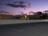 a city skyline and parking lot at dusk with traffic lights on and an orange fire hydrant