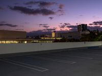 a city skyline and parking lot at dusk with traffic lights on and an orange fire hydrant