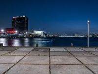 a large, square cement walkway next to a body of water with a fire hydrant and a city skyline in the distance