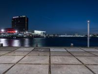 a large, square cement walkway next to a body of water with a fire hydrant and a city skyline in the distance