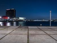 a large, square cement walkway next to a body of water with a fire hydrant and a city skyline in the distance