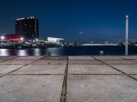 a large, square cement walkway next to a body of water with a fire hydrant and a city skyline in the distance