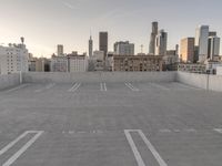 a large empty parking lot is on a concrete lot with city buildings in the background