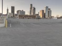 a large empty parking lot is on a concrete lot with city buildings in the background