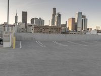 a large empty parking lot is on a concrete lot with city buildings in the background