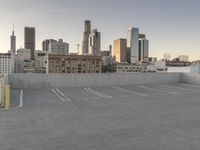 a large empty parking lot is on a concrete lot with city buildings in the background