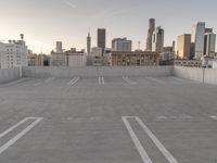 a large empty parking lot is on a concrete lot with city buildings in the background