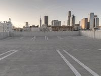 a large empty parking lot is on a concrete lot with city buildings in the background