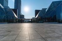 an empty square on top of a building with windows in the middle and one half half reflecting the sun