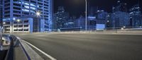 a very empty road near some tall buildings at night in the city of vancouver, canada