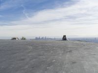 people sitting on a rock overlooking a city skyline and a hill with a skateboard