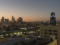 the sunset over the city skyline and a tower with a light on it's side