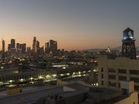 the sunset over the city skyline and a tower with a light on it's side