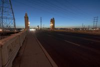 the view at night of an empty highway through a bridge and power lines on a clear day