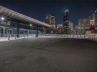 the empty parking lot is under a bridge with the city in the background behind it