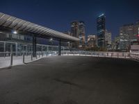 the empty parking lot is under a bridge with the city in the background behind it