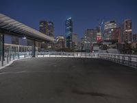 the empty parking lot is under a bridge with the city in the background behind it