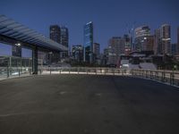 the empty parking lot is under a bridge with the city in the background behind it