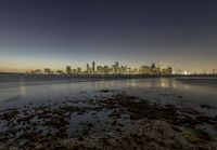 an evening view of a city skyline and the ocean with low tide on a beach