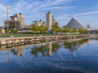 the skyline is reflected in the calm waters of the water, as a person skateboards