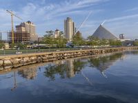 the skyline is reflected in the calm waters of the water, as a person skateboards