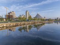 the skyline is reflected in the calm waters of the water, as a person skateboards