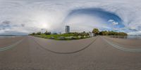 a fish eye lens photograph of a road in front of the city skyline on a cloudy day