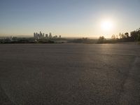 the sun sets over the city skyline in a beachfront area of a fenced off parking lot