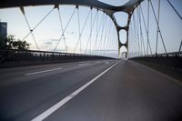 a car going over a bridge at sunset with city skyline in the background as seen from a moving vehicle