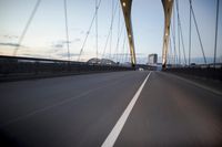 a car going over a bridge at sunset with city skyline in the background as seen from a moving vehicle
