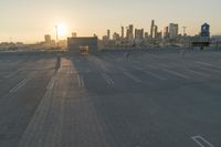 an empty parking lot overlooking the city skyline at sunset time with an airplane taking off