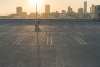 an empty parking lot overlooking the city skyline at sunset time with an airplane taking off