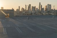 an empty parking lot overlooking the city skyline at sunset time with an airplane taking off