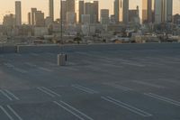 an empty parking lot overlooking the city skyline at sunset time with an airplane taking off